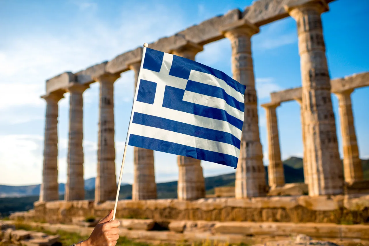 greek flag in front of the temple of poseidon at sounion