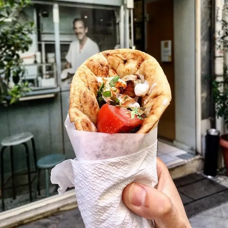 All Inclusive 8-Hour Private Tour In Athens 14 Traditional Greek gyro wrap filled with seasoned rotisserie meat, fresh tomatoes, onions, crispy fries, and creamy tzatziki sauce, wrapped in a warm, charred pita.